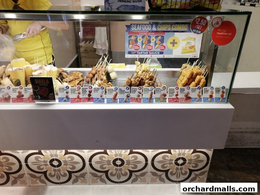 A display case filled with various fried snacks on sticks, with prices and descriptions visible.