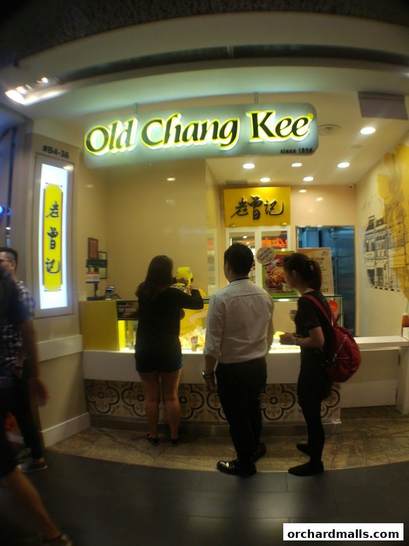 Customers ordering at the Old Chang Kee food stall with its distinctive yellow signage.