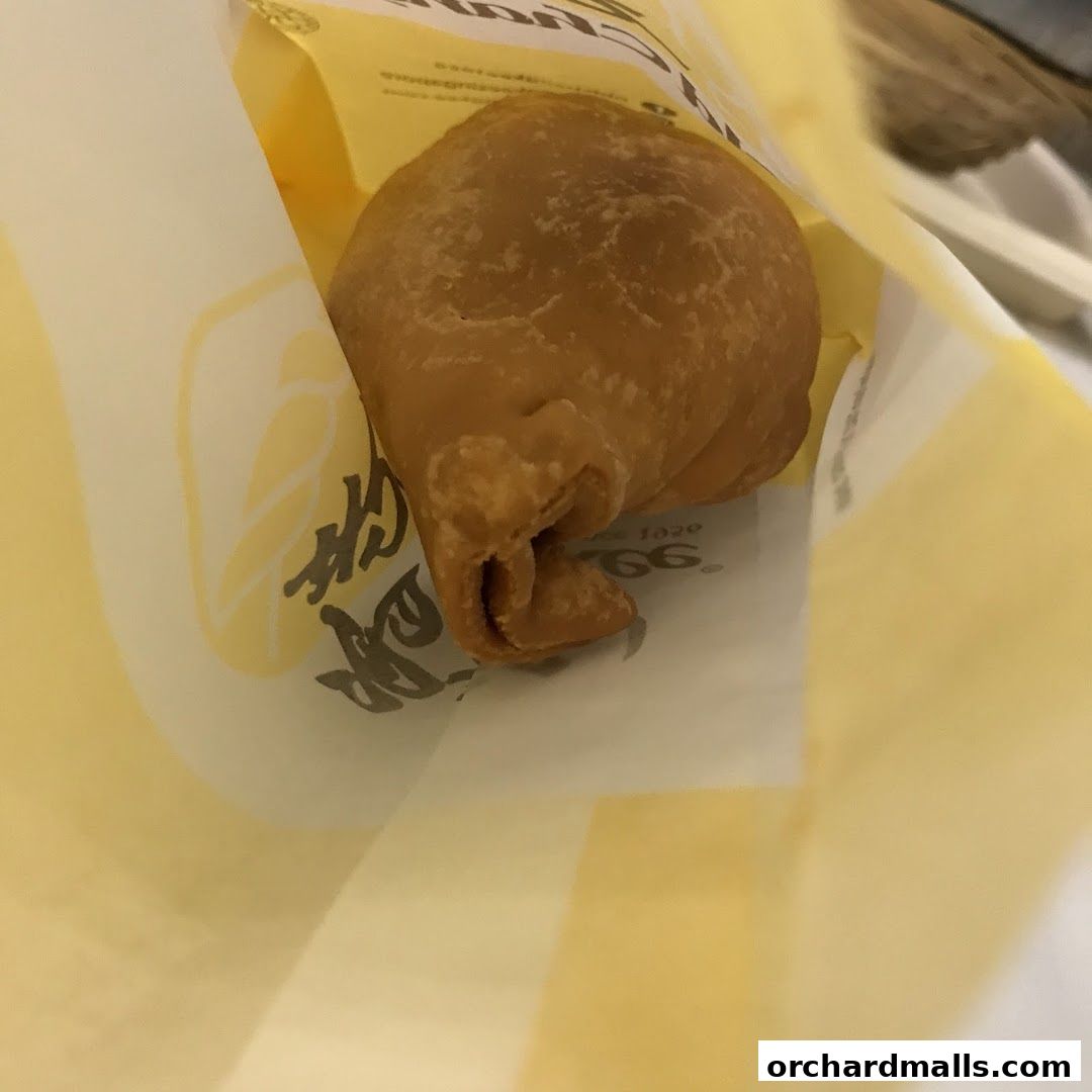 A close-up of a golden-brown pastry in a yellow Old Chang Kee paper bag.