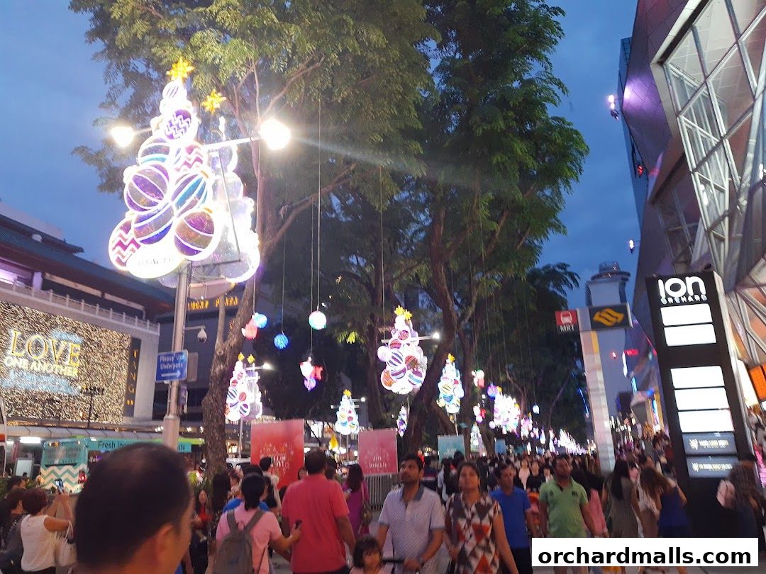 A bustling street scene at dusk, adorned with festive Christmas tree lights and decorations.