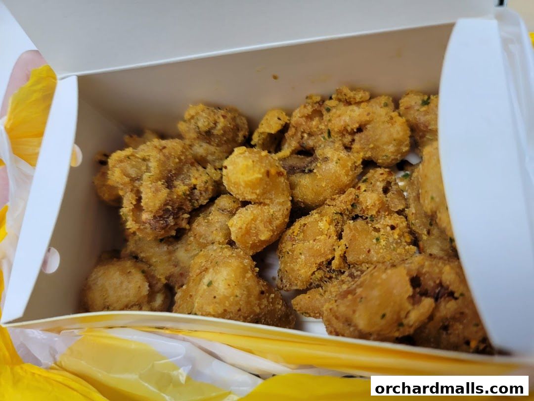 A white box filled with crispy, golden-brown fried chicken pieces seasoned with herbs.