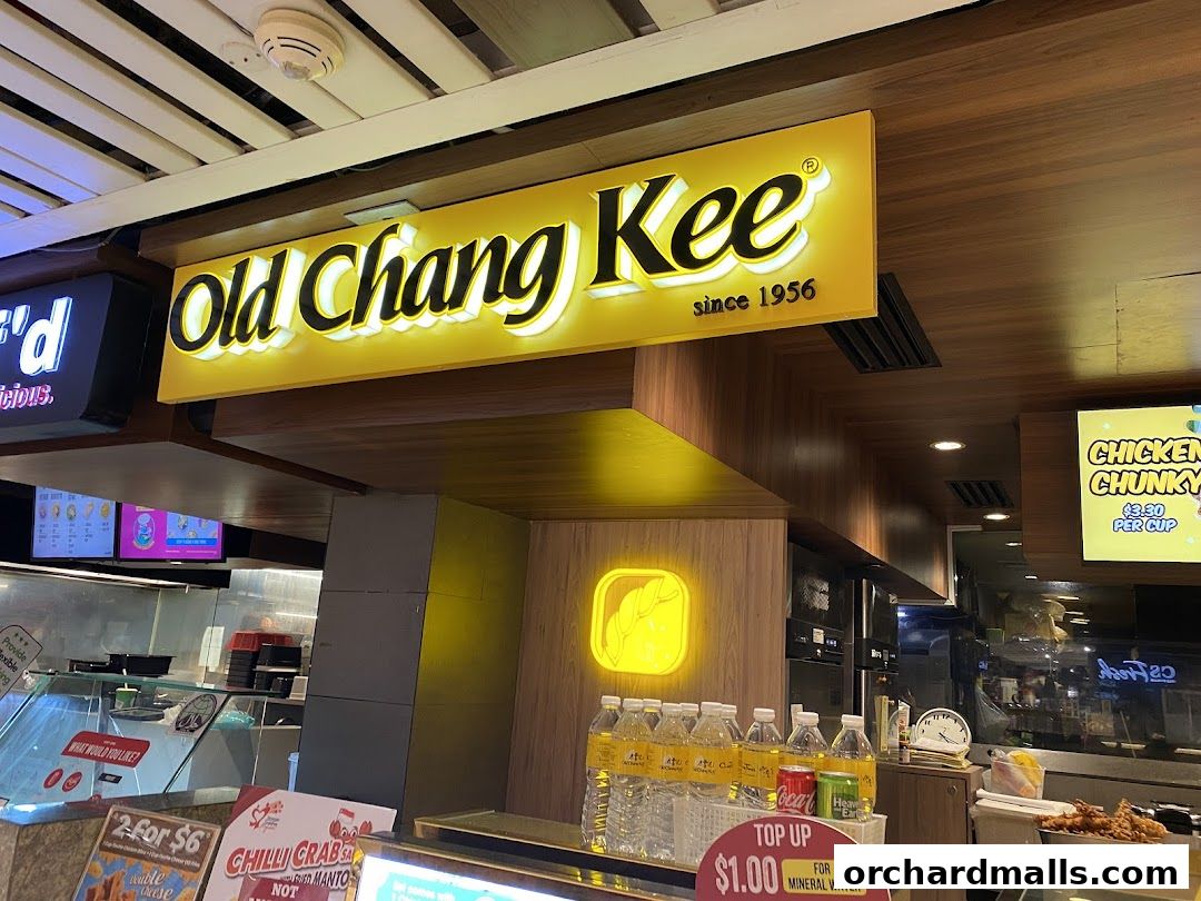 The Old Chang Kee shop front with its iconic yellow sign and display of drinks and food items.