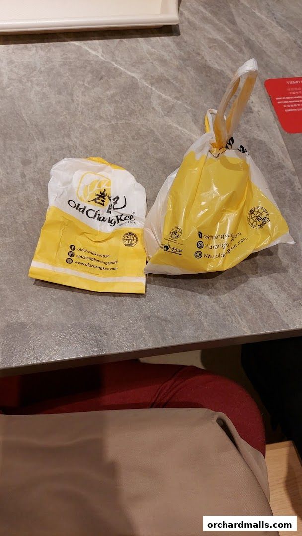Two takeaway bags from Old Chang Kee on a marble table.