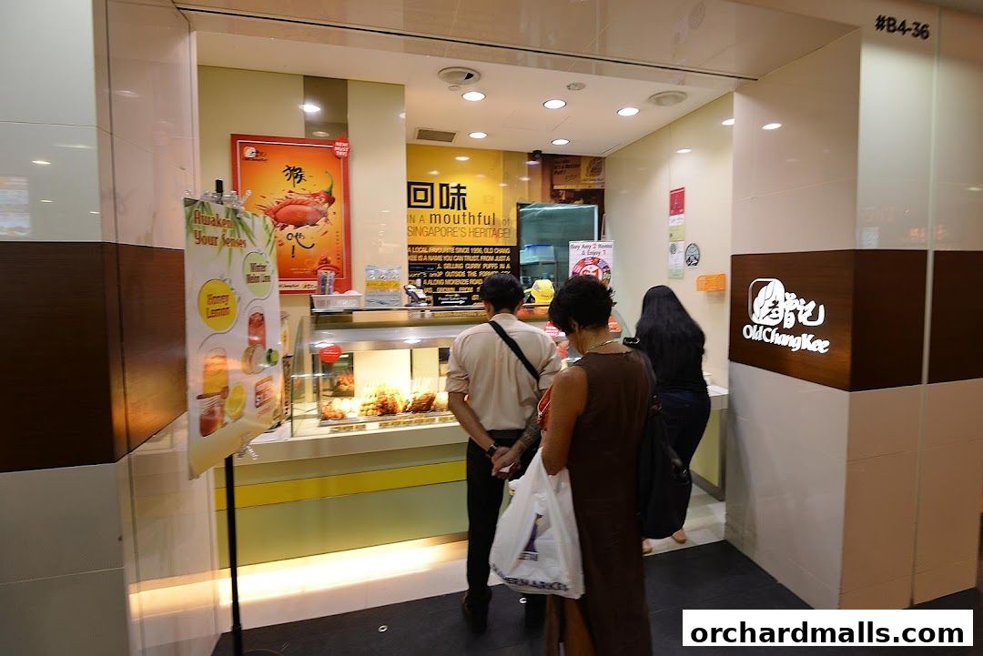 Customers are queuing at the Old Chang Kee food stall, which displays its signature curry puffs and drinks.