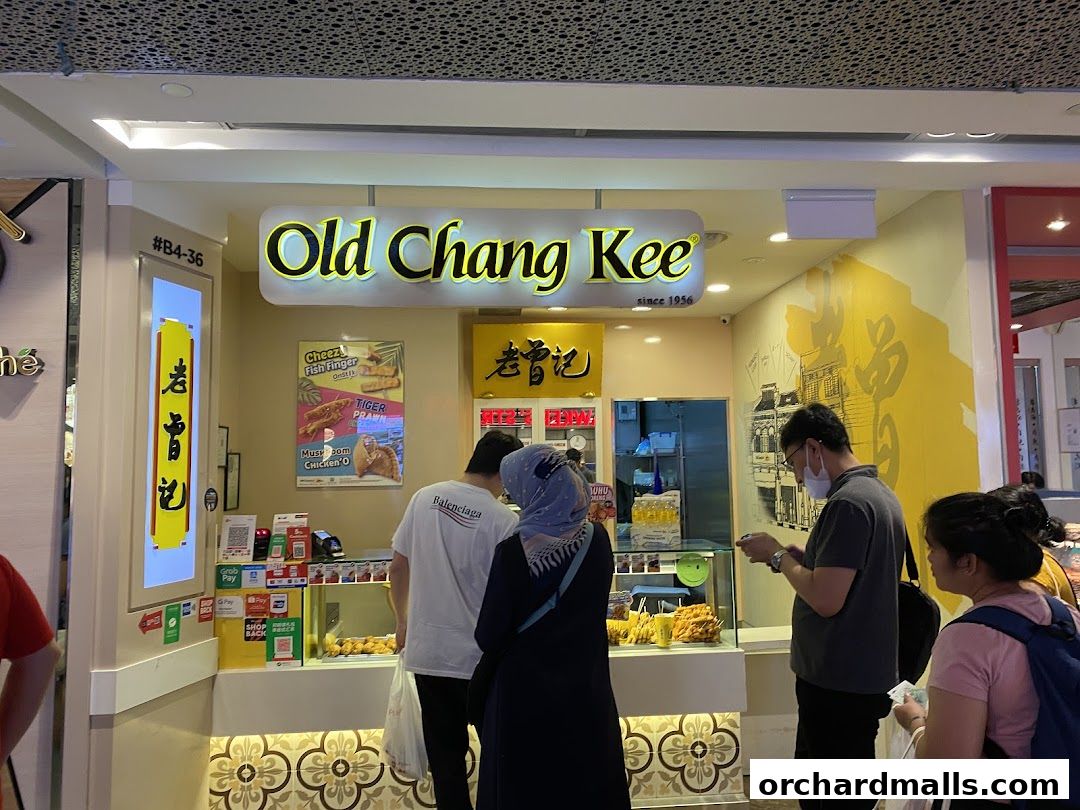 People queuing at the Old Chang Kee shop, with food displays and payment options visible.