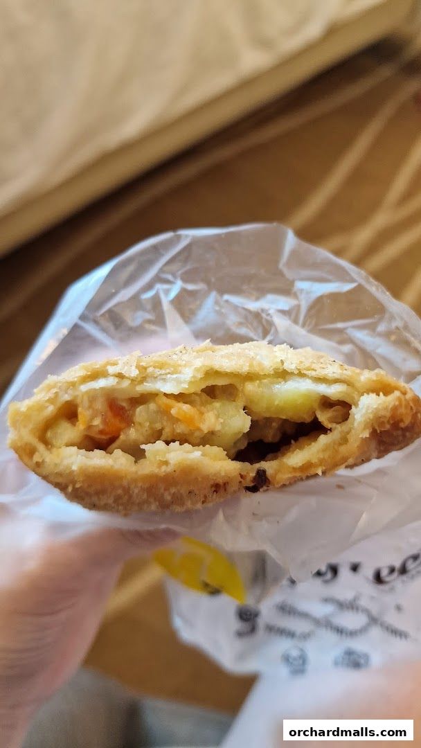 A close-up shot of a person holding a delicious-looking curry puff from Old Chang Kee.