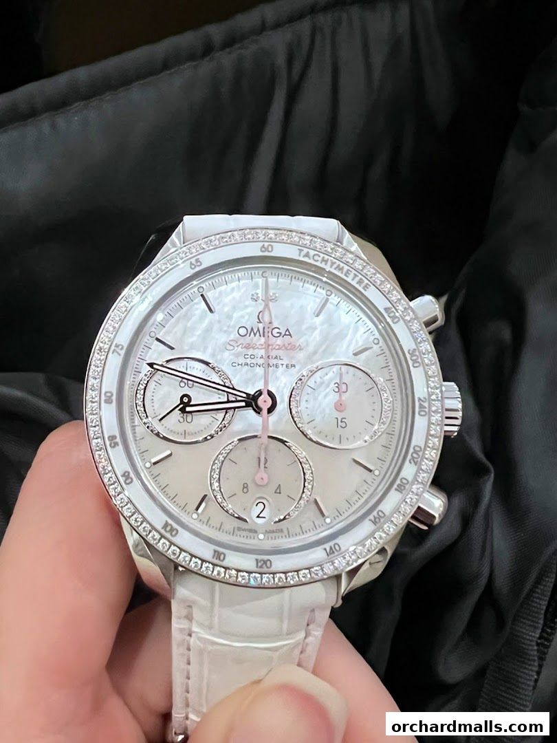 A close-up of an OMEGA Speedmaster watch with a white dial and diamond bezel.