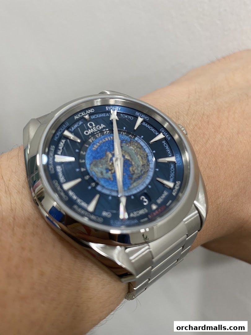 A close-up shot of an OMEGA watch with a world time complication on a wrist.