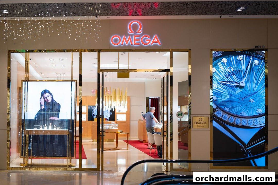 The OMEGA boutique entrance features a large digital display of a watch and an interior view of luxury timepieces.