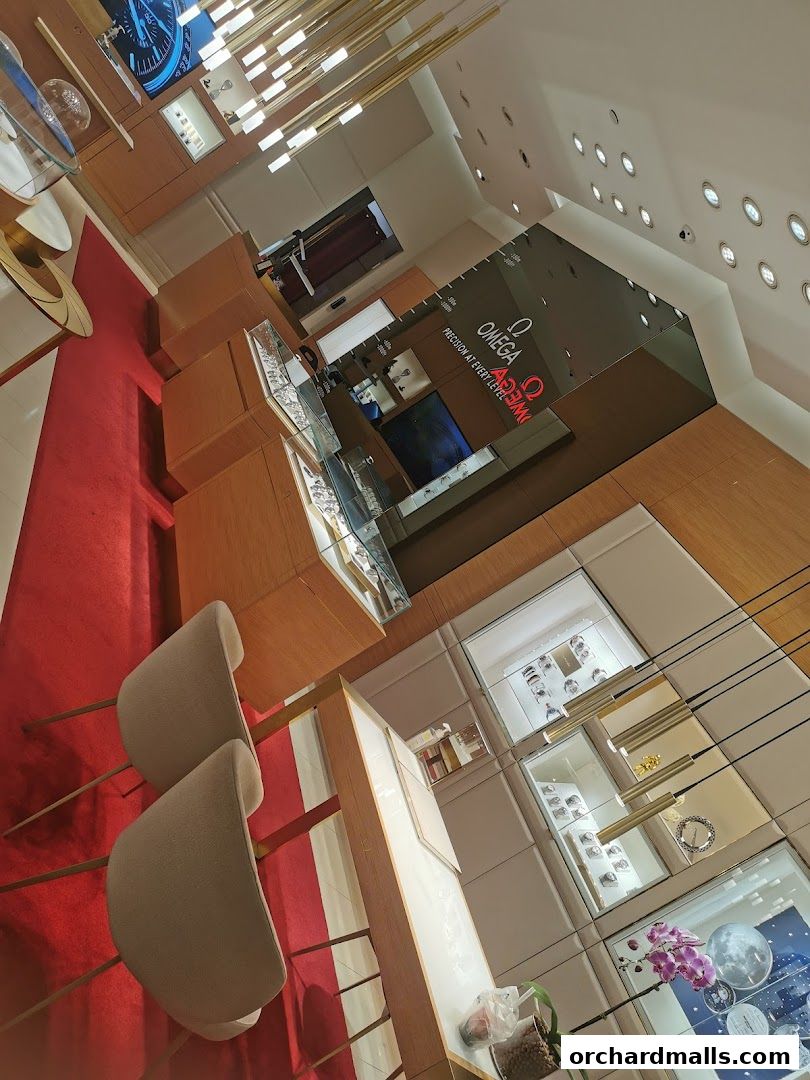 Interior view of an OMEGA watch store with display cases and seating.