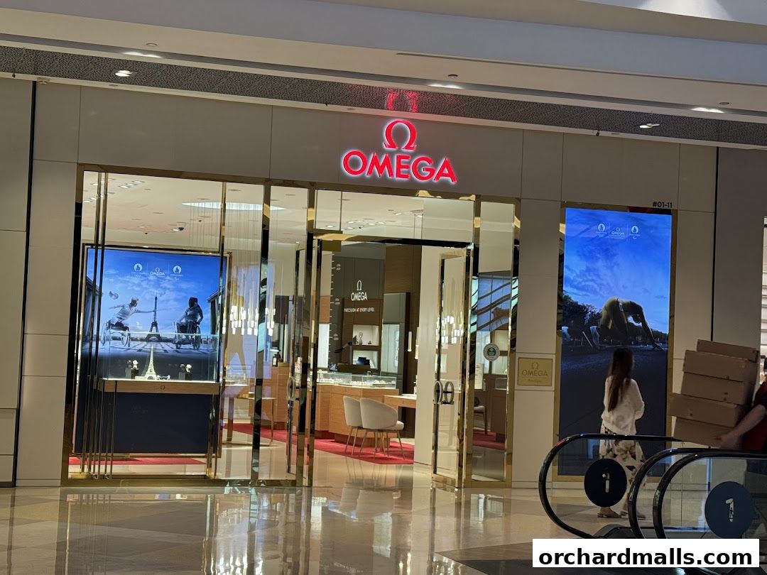The OMEGA store features a modern facade with illuminated signage and large display windows showcasing watches.