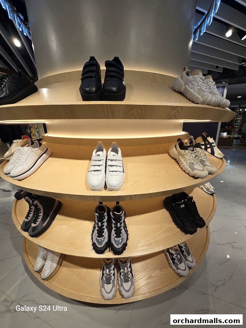 A display of various Onitsuka Tiger sneakers on tiered wooden shelves.