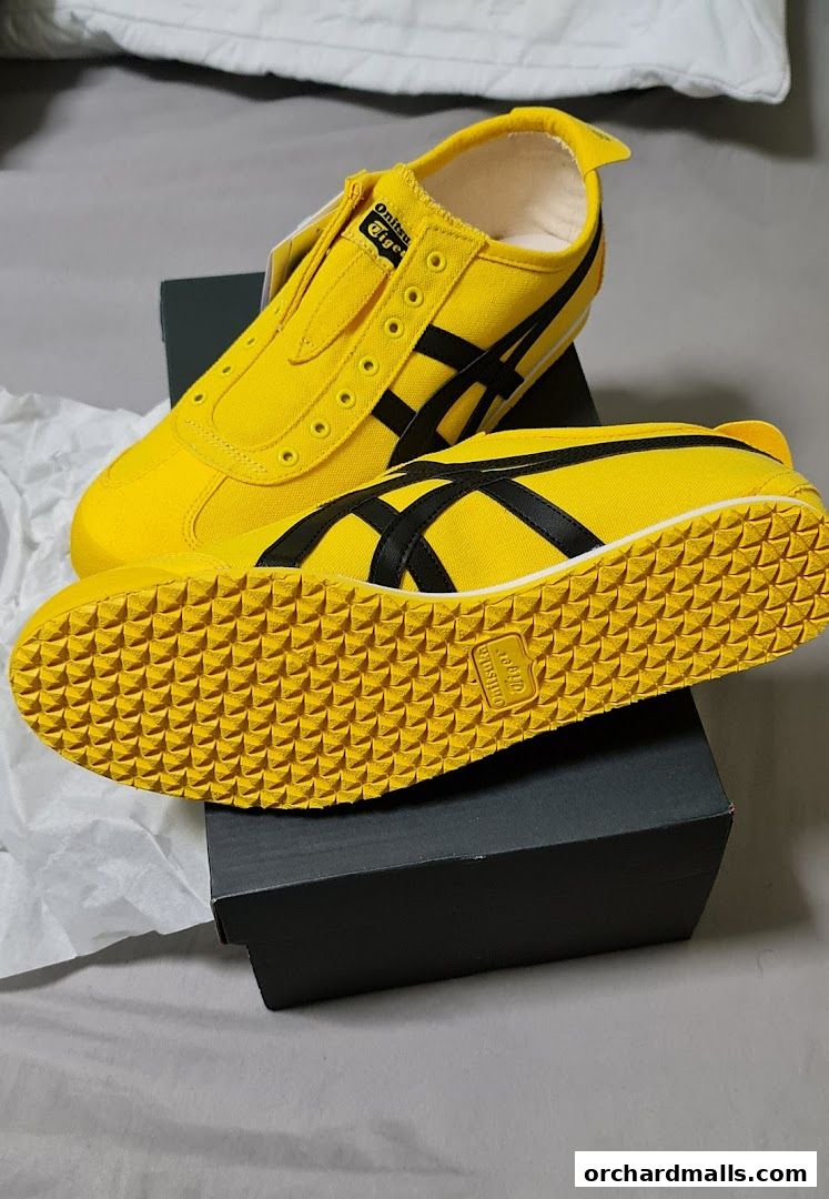 A pair of bright yellow Onitsuka Tiger sneakers with black stripes on a shoe box.