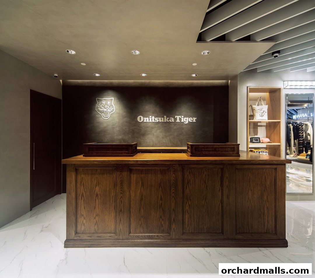 The interior of an Onitsuka Tiger store with a wooden counter and branded wall.