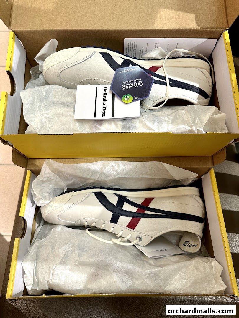 Two pairs of white Onitsuka Tiger sneakers in their boxes, showcasing classic design.