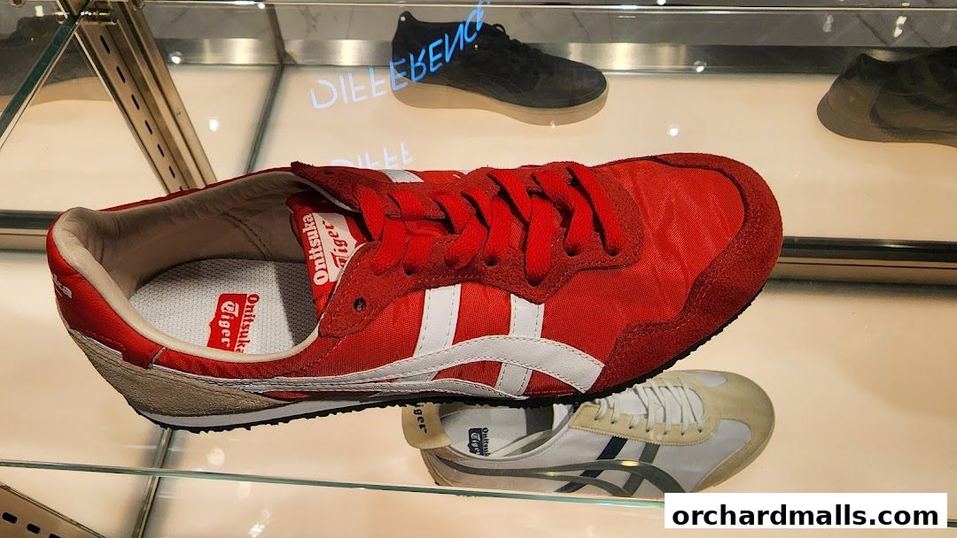 Close-up of red and white Onitsuka Tiger sneakers displayed in a shop window.