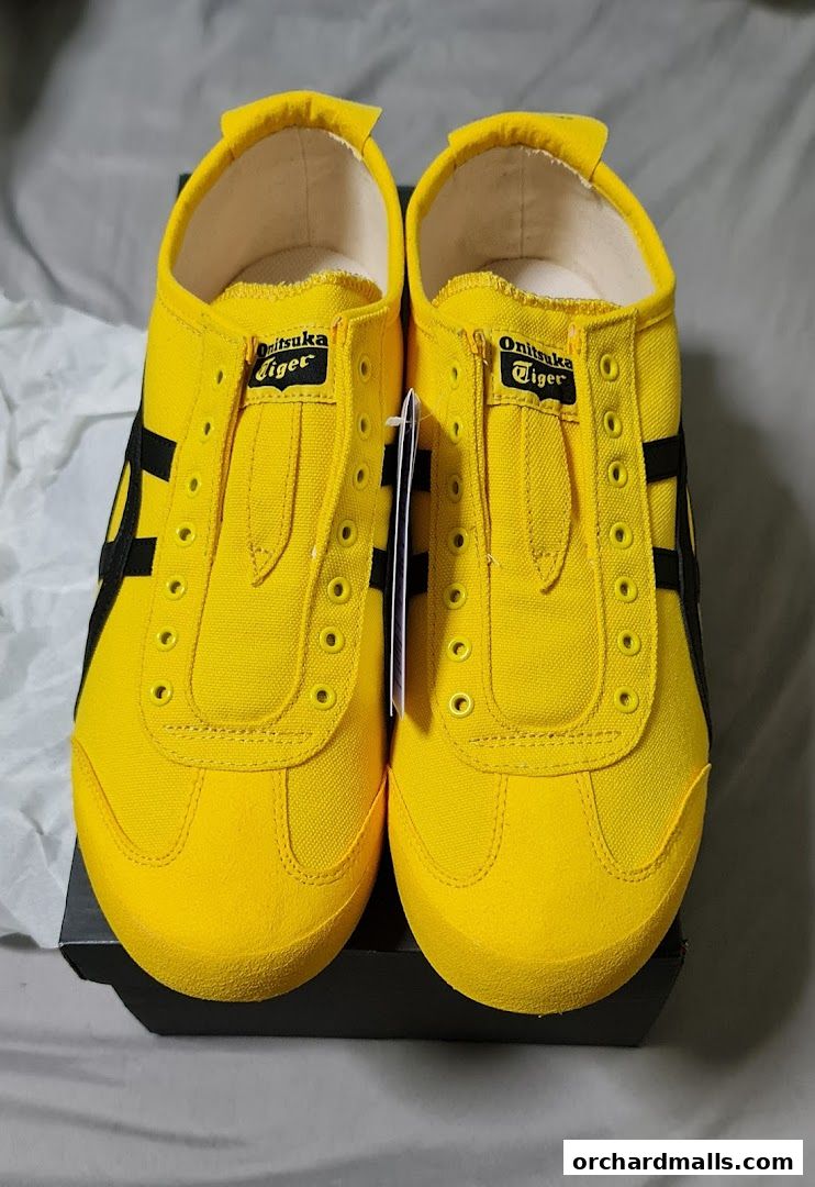 A pair of bright yellow Onitsuka Tiger sneakers with black stripes, displayed on a box.