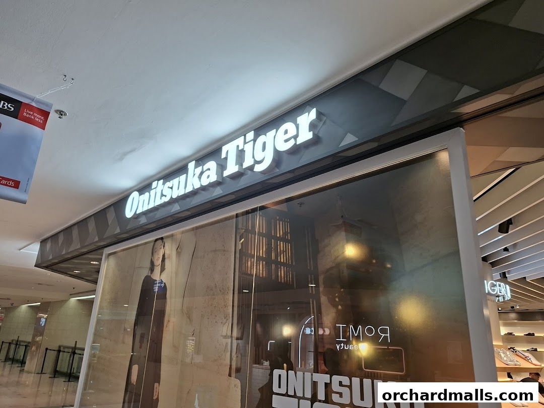The illuminated Onitsuka Tiger sign above a shop window displaying fashion.