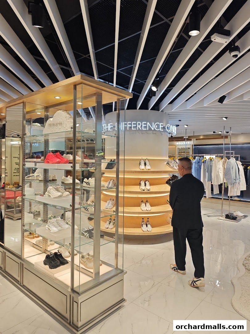 Interior of a modern Onitsuka Tiger shoe store with a man browsing.