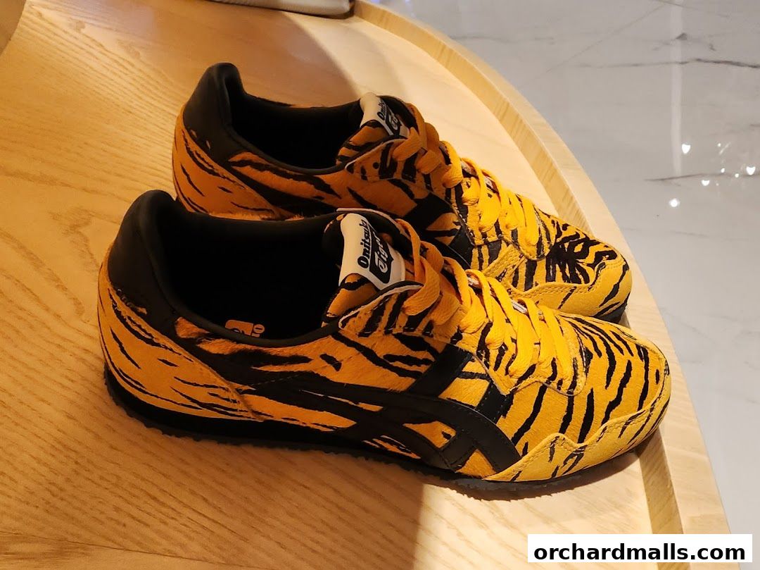 Onitsuka Tiger sneakers with a bold tiger stripe pattern on a wooden display.