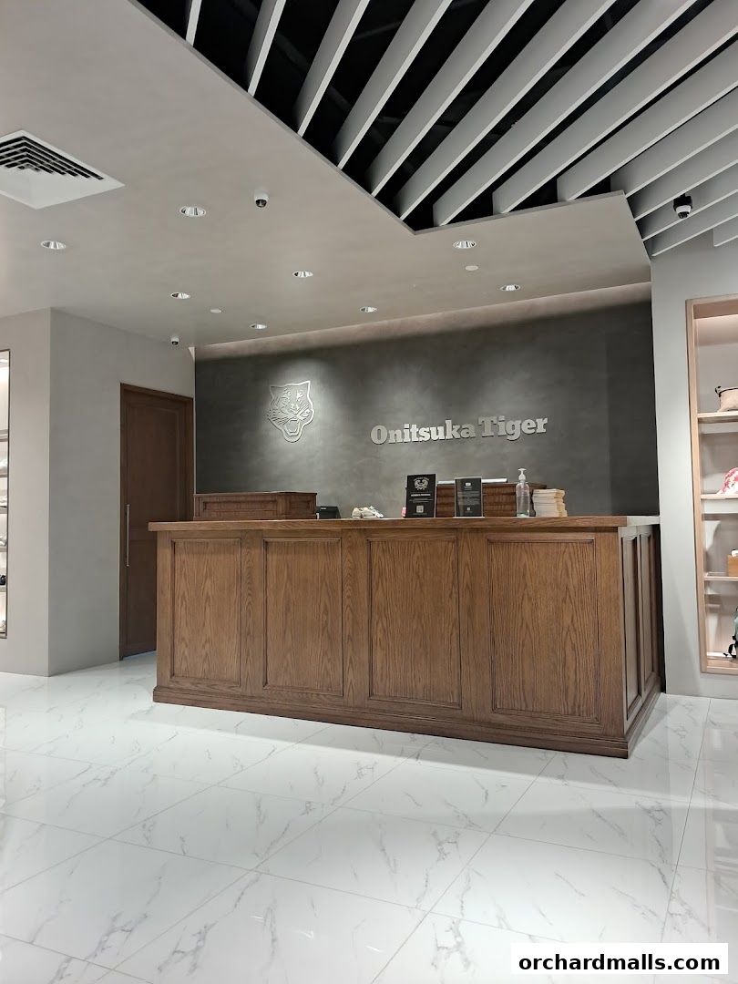Onitsuka Tiger store interior with a wooden counter and branded wall.
