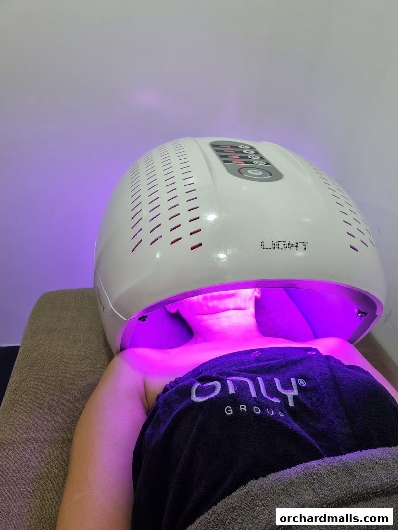 A person receives a light therapy treatment under a large, white device.