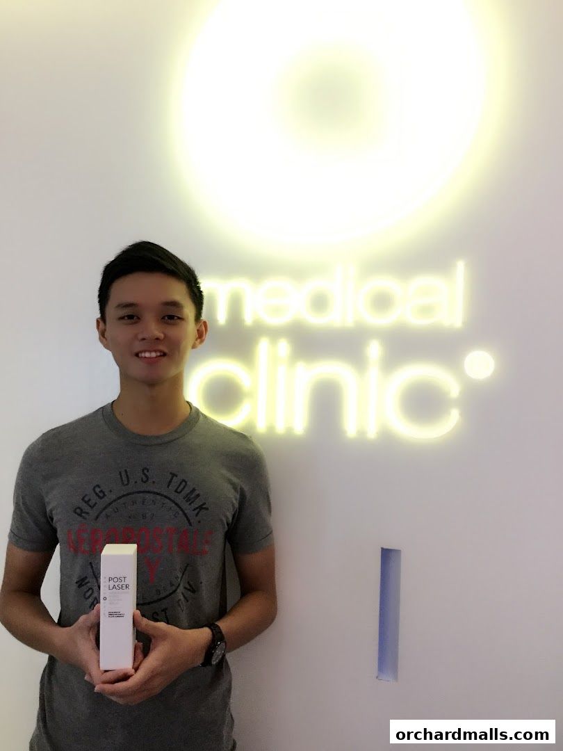 A man holds a skincare product in front of a glowing 'medical clinic' sign.