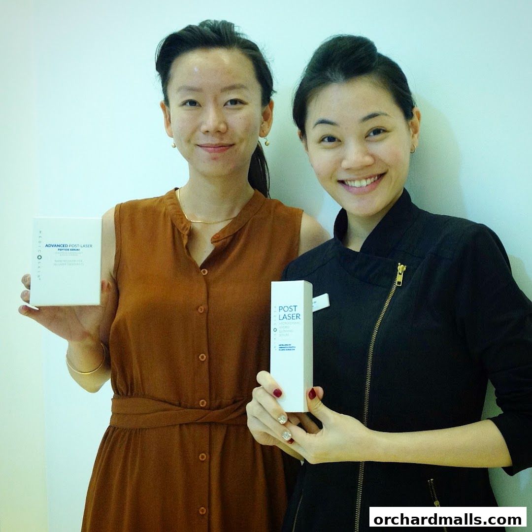 Two women smiling and holding boxes of post-laser skincare products.