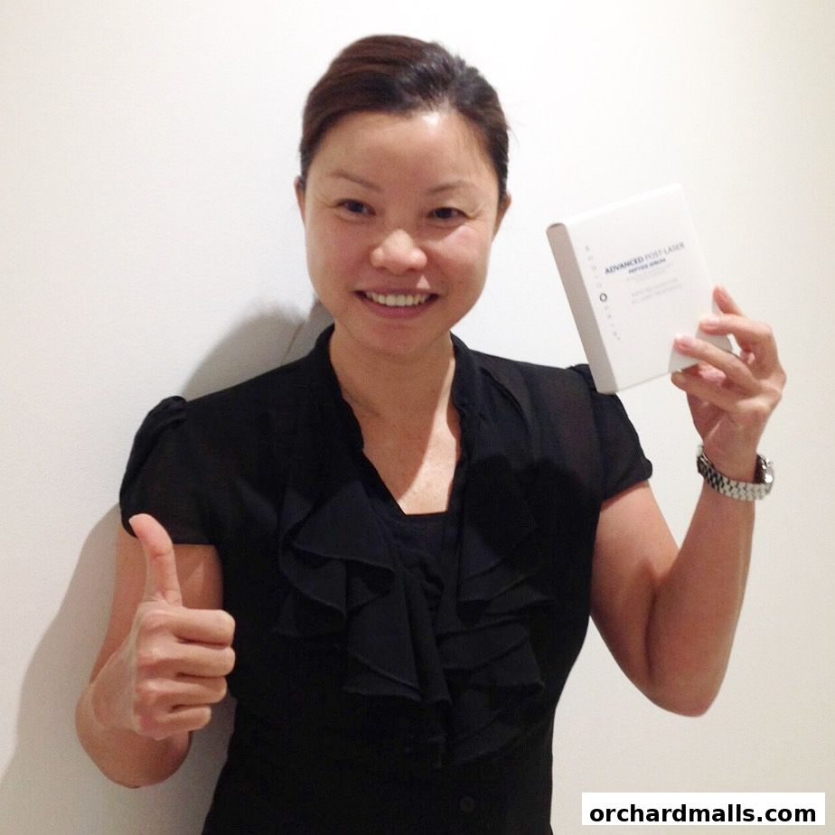 A woman smiles and gives a thumbs up while holding a product box.