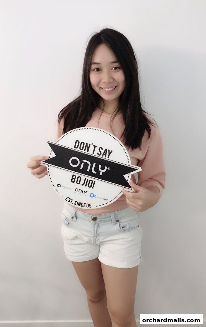 A young woman holds a circular sign with text and logos for 'Only Aesthetics'.