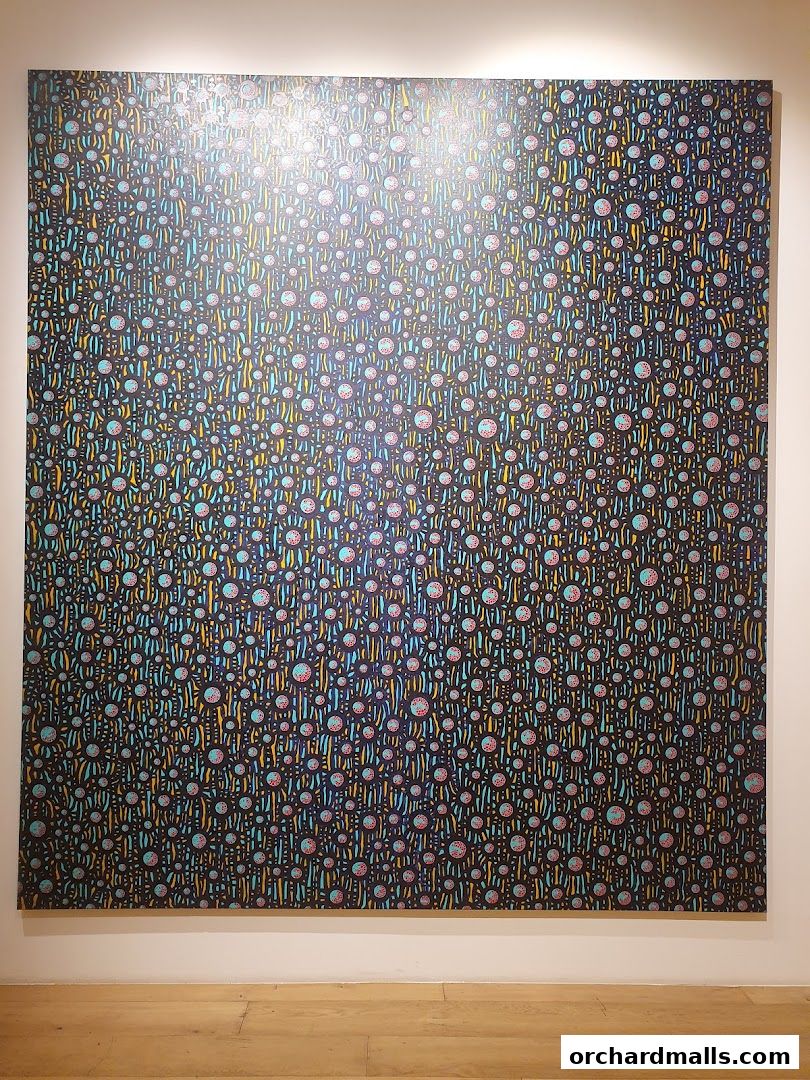 A large, colorful abstract painting with a dark background and repeating circular and linear patterns.