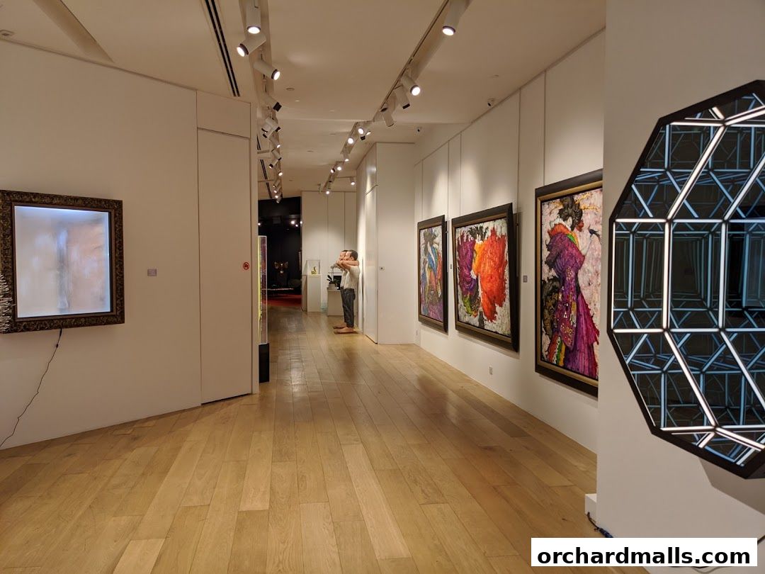 Interior view of an art gallery with paintings and a geometric light installation.