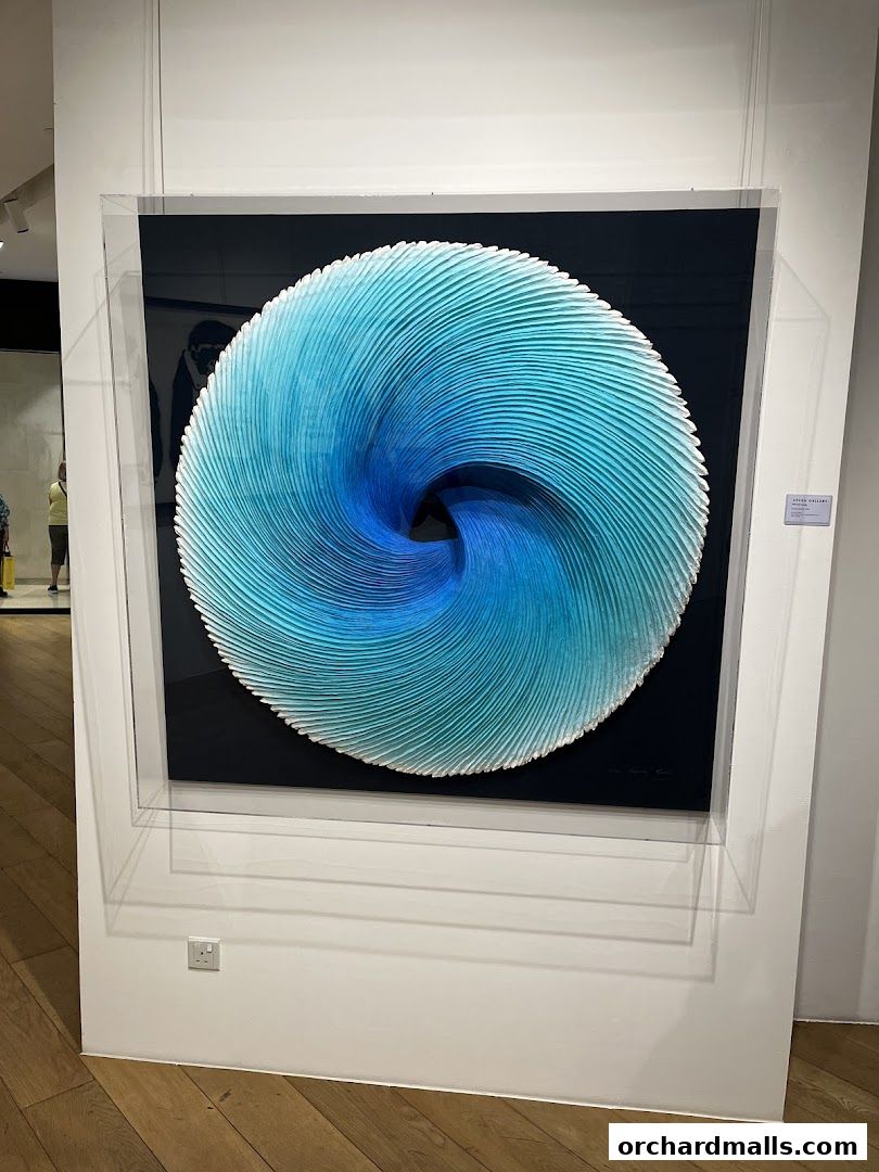 A striking blue and white circular sculpture displayed in a gallery setting.