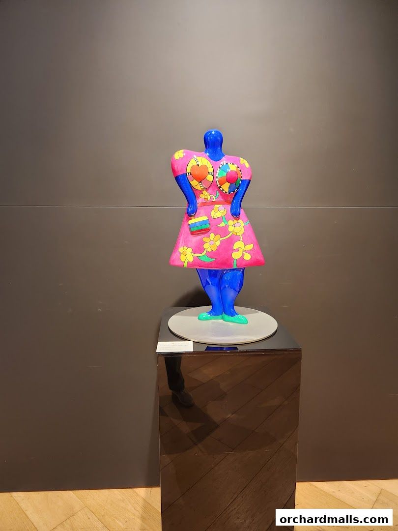 A vibrant blue sculpture of a woman in a pink floral dress on display.