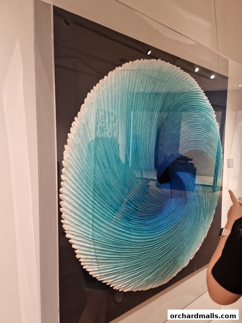 A striking blue and white textured artwork displayed in a gallery setting.