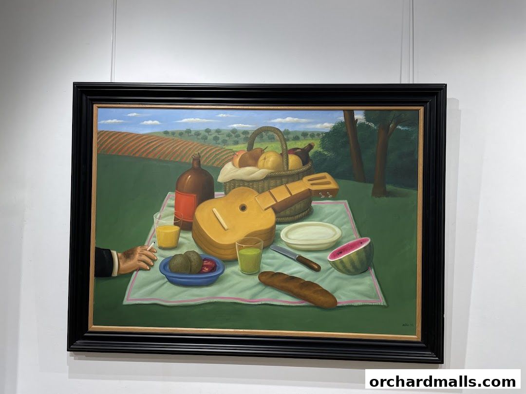 A framed painting of a picnic scene with a guitar, fruit basket, and food on a blanket.