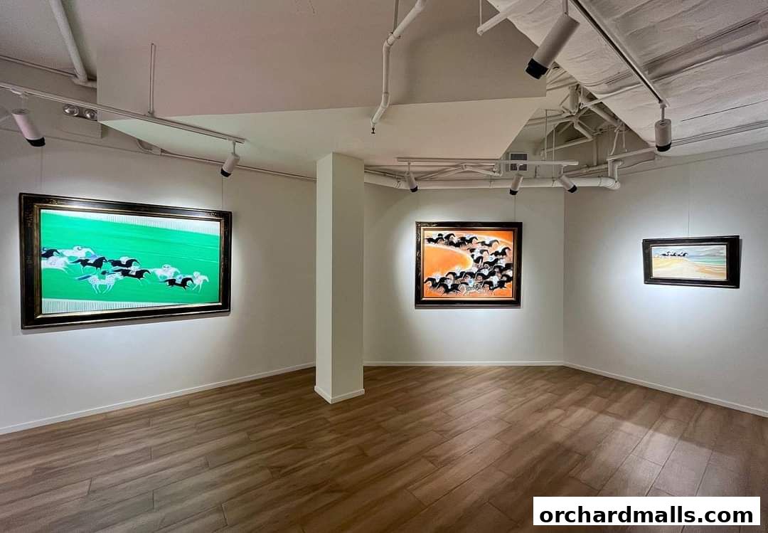 Interior view of an art gallery with three framed paintings of horses on display.