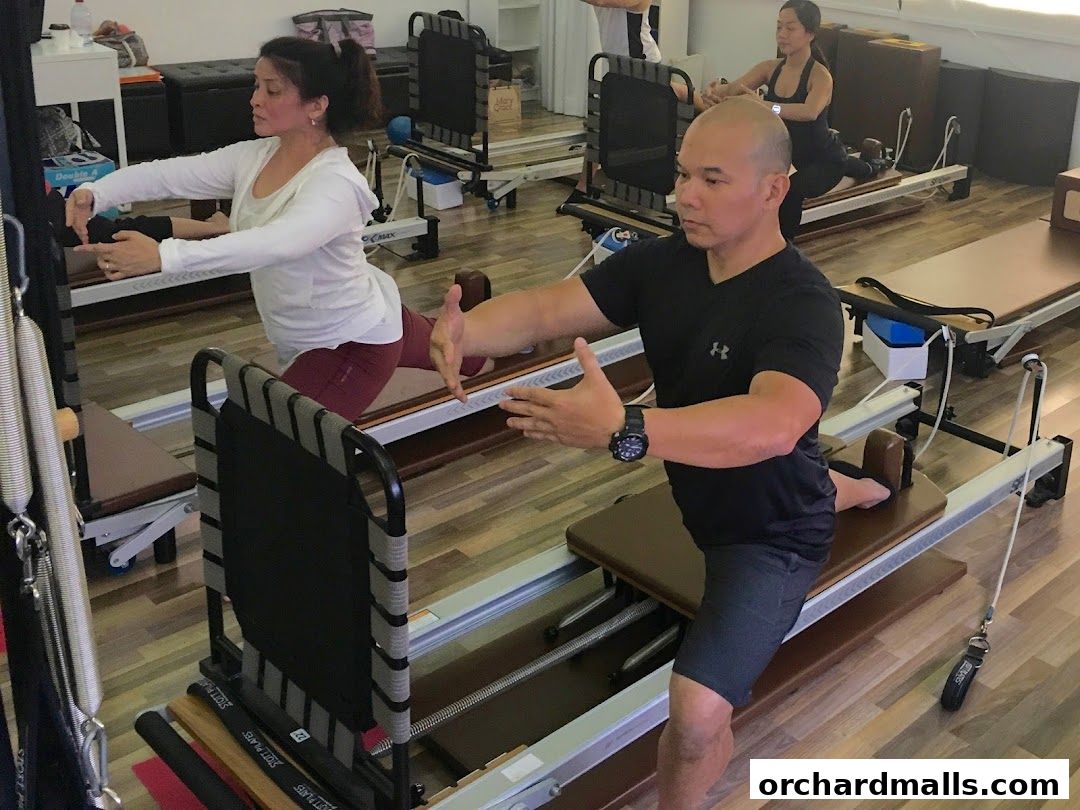 People practicing Pilates on reformers in a bright, modern studio.