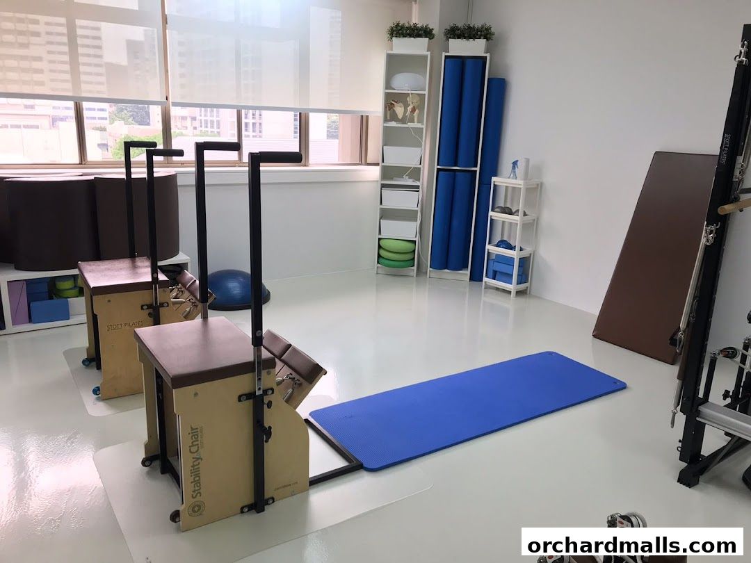 Interior of a bright Pilates studio with reformers, mats, and storage shelves.