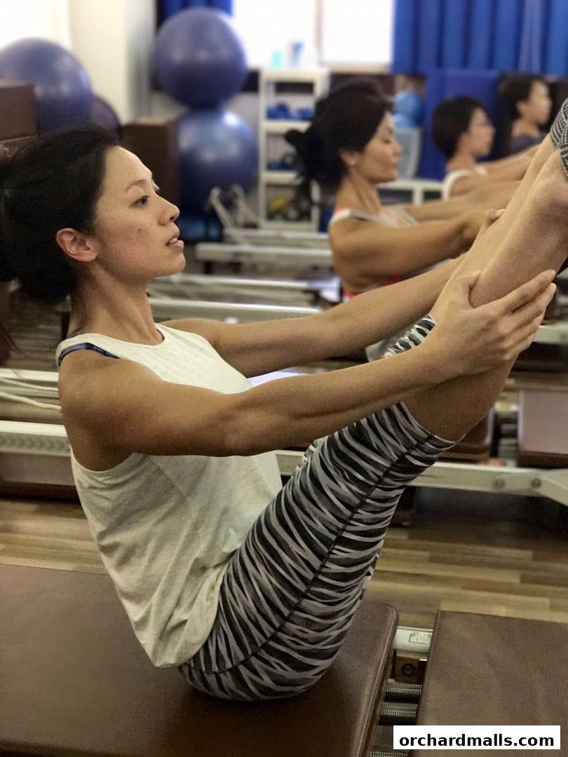 Women performing a Pilates exercise on reformers in a studio with exercise balls.
