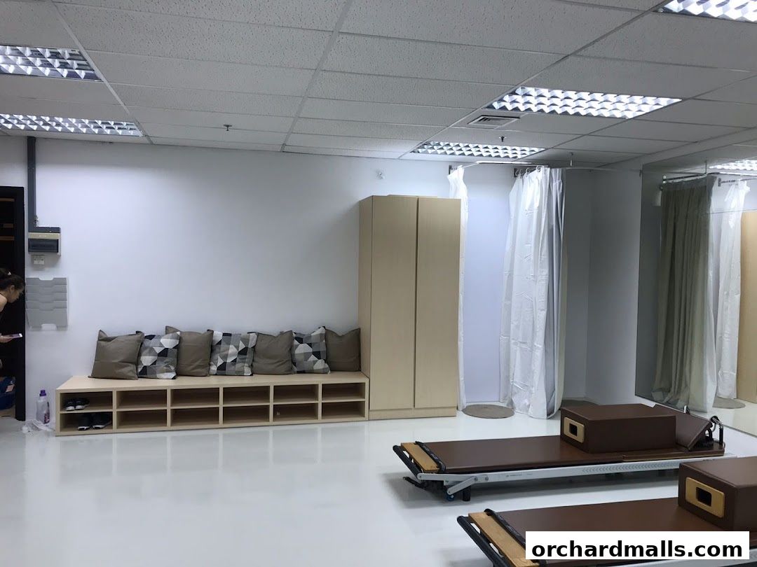 Interior of a Pilates studio with reformers, a bench with cushions, and changing cubicles.
