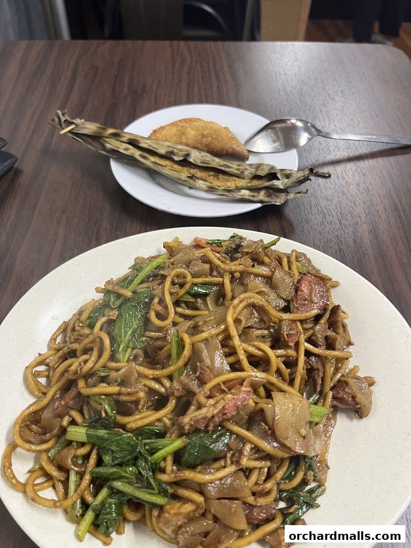 A plate of noodles and a small pastry on a table at Orchard Deli Cafe.