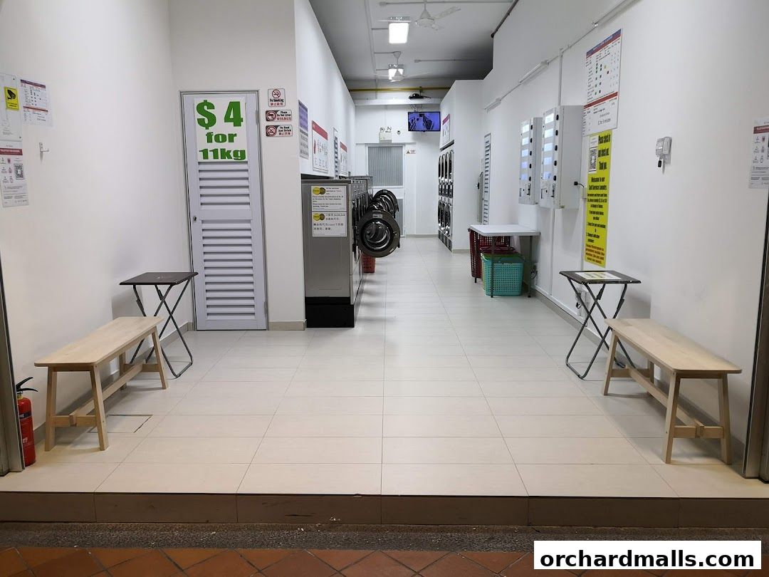 Interior view of a laundromat with washing machines, dryers, and seating areas.