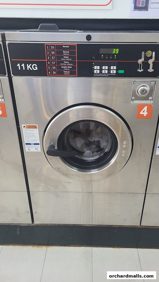 A close-up of a commercial washing machine with a price list for wash programs.