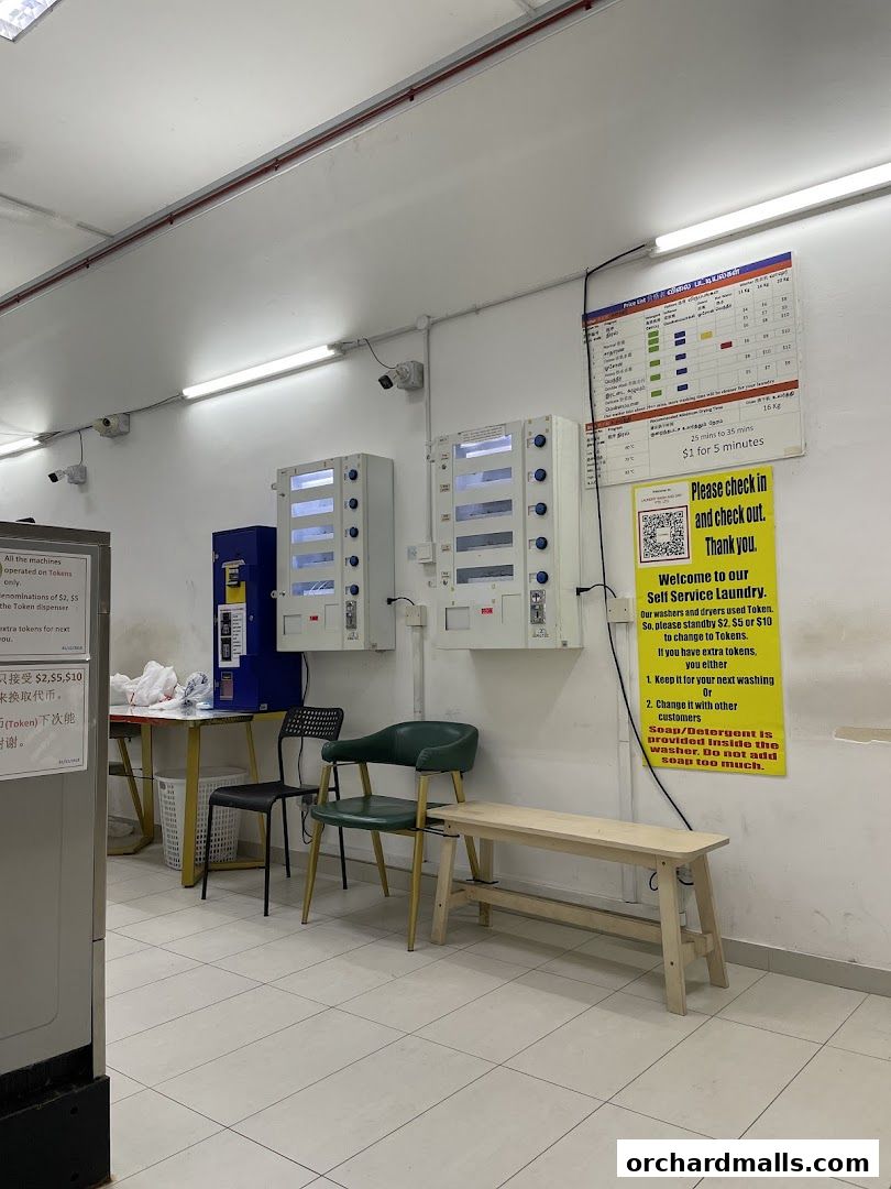 Interior of a self-service laundry with washing machines, token dispensers, and seating.