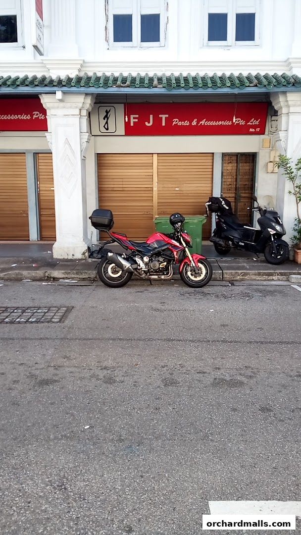 A red motorcycle and a black scooter parked in front of a shop with closed shutters.