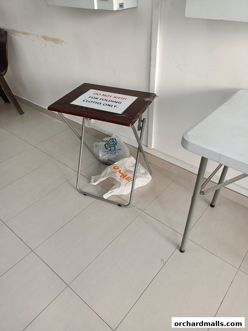 A folding table with a sign that says 'DO NOT SIT!!! FOR FOLDING CLOTHS ONLY.'