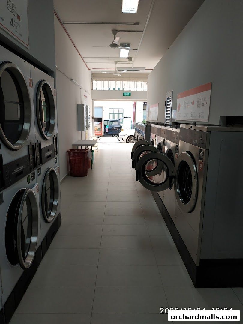 Interior view of a laundromat with rows of washing machines and dryers.