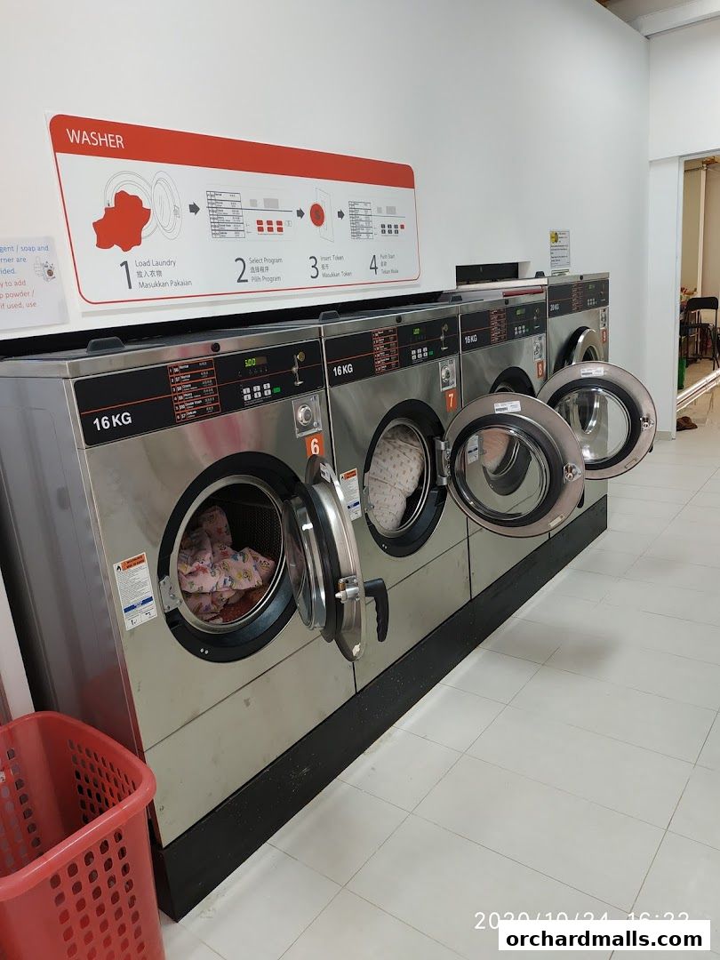 Row of commercial washing machines with instructions and a red laundry basket.