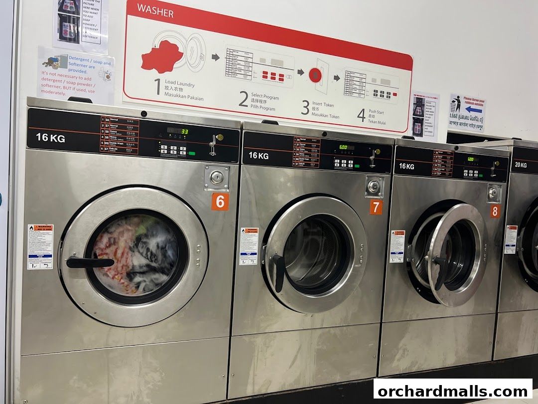 Row of commercial washing machines with instructions and capacity labels.